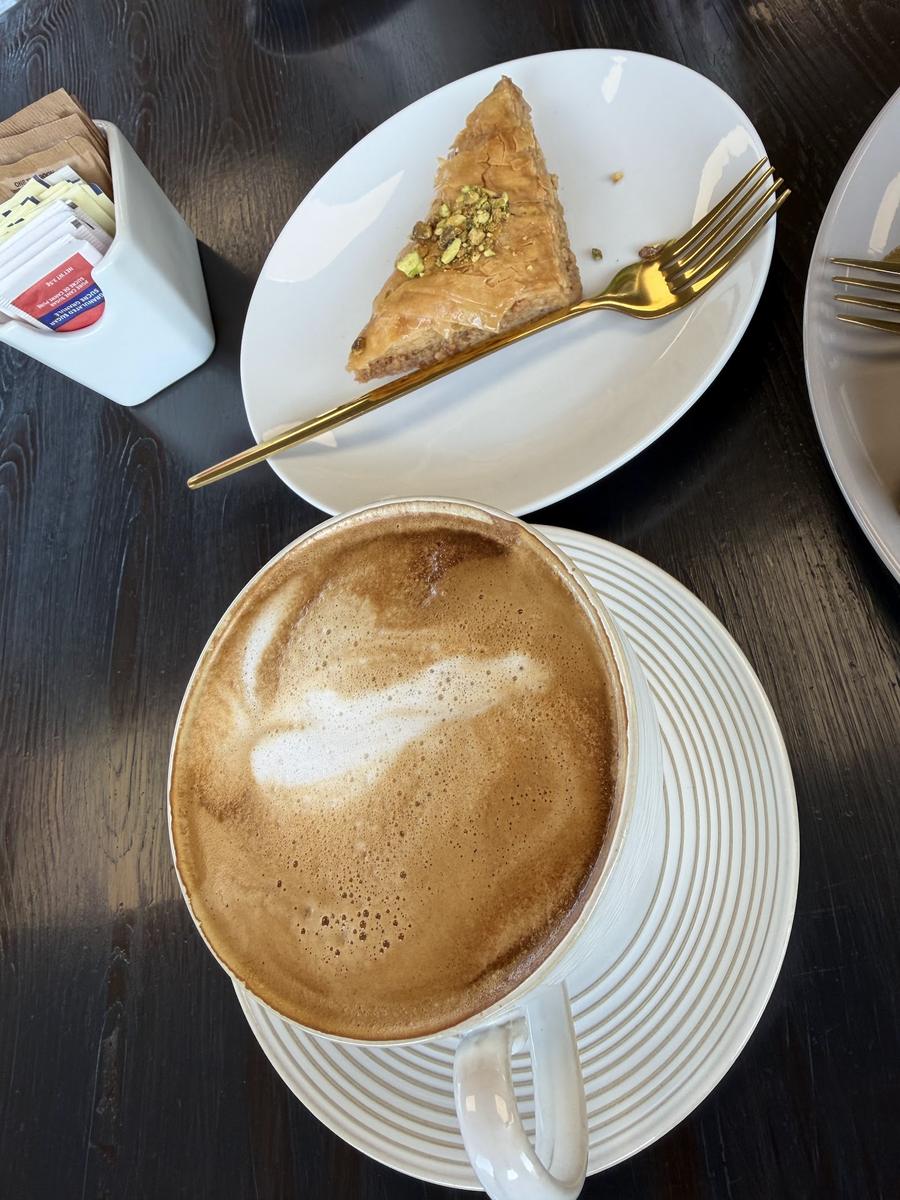 Cappuccino with latte art next to baklava