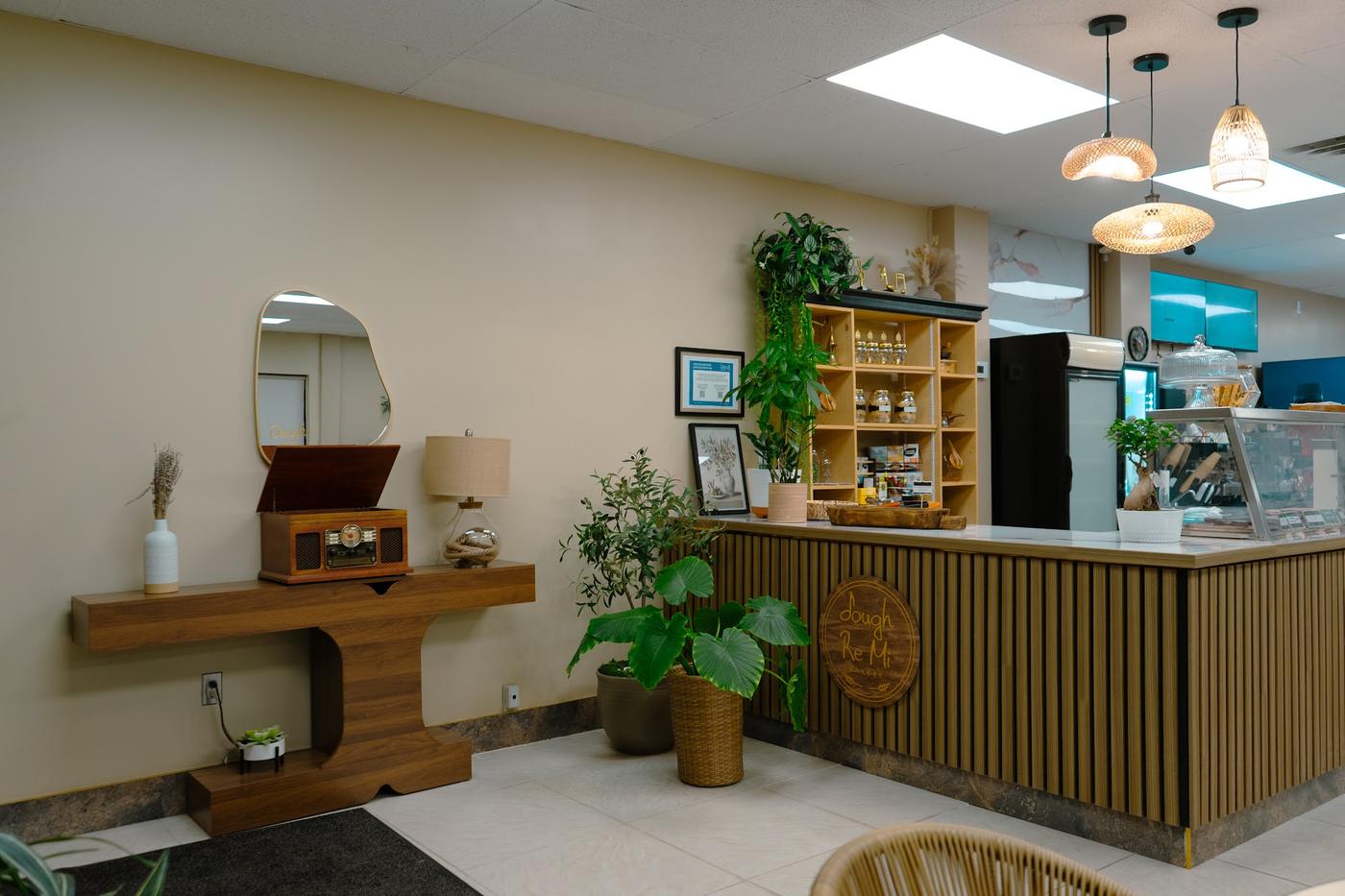 Inside Dough Re Mi: a walnut console with a vintage record player, plants, and the slatted wood counter with the café's logo