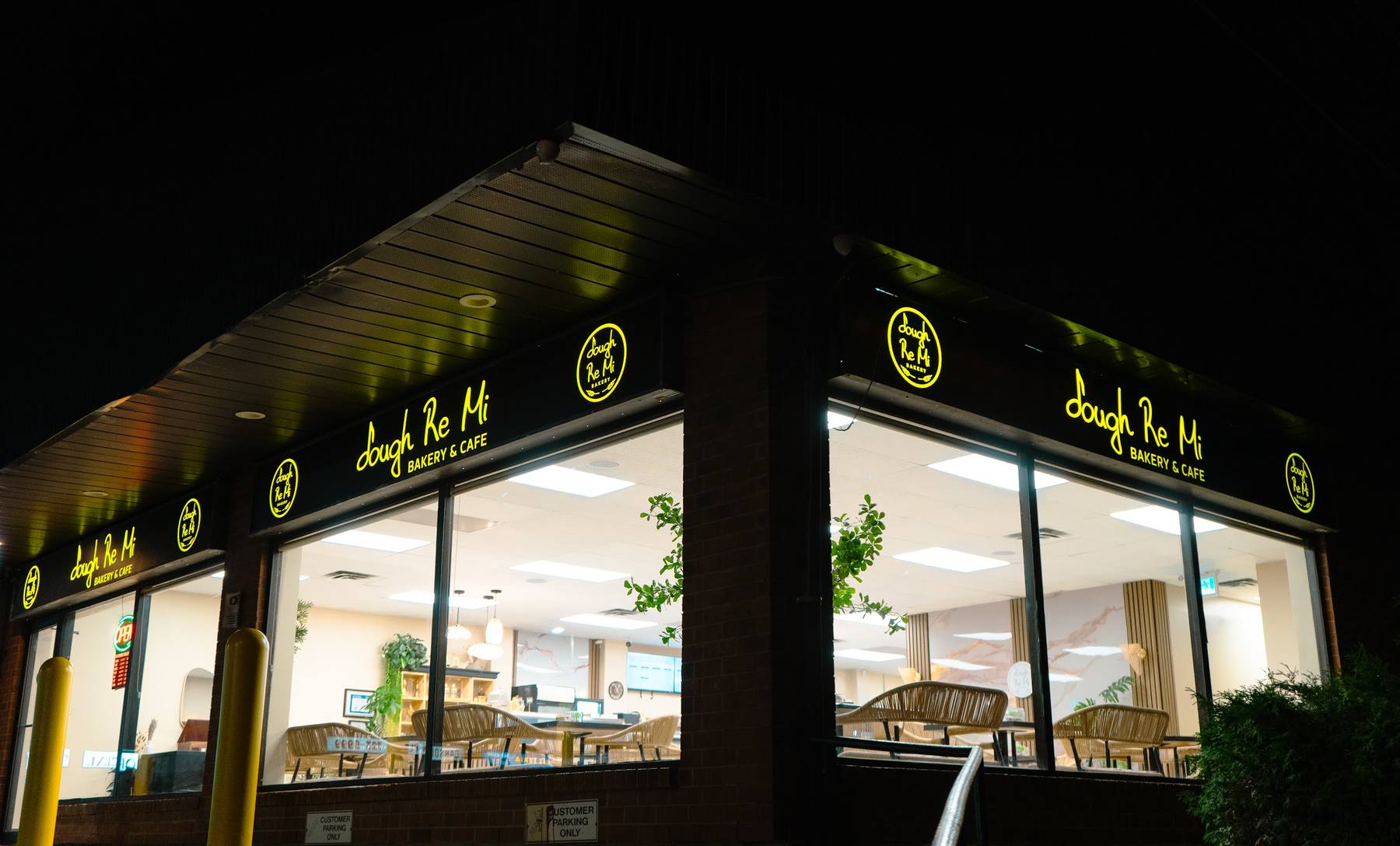 Dough Re Mi storefront at night, with the lit logo signs above the windows
